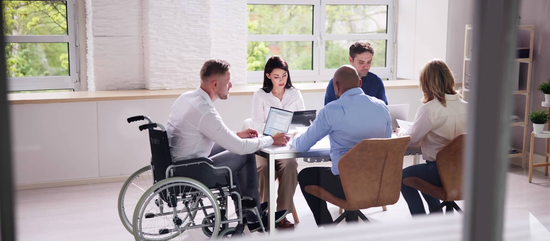 Groupe diversifié et paritaire en réunion réalisant un travail collaboratif pour garantir l’accessibilité et l’égalité des droits en entreprise.