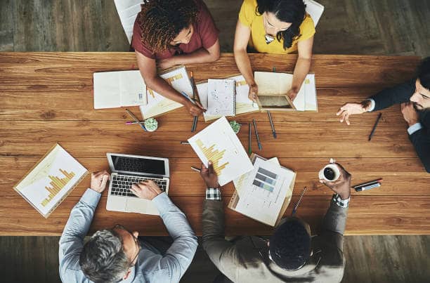  Des personnes partagent des graphiques sur une table lors d’une formation interactive sur la visualisation de données économiques.