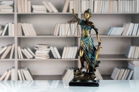 Bibliothèque avec une sculpture de la justice au premier plan, illustrant une newsletter personnalisée pour informer sur les nouvelles obligations légales.